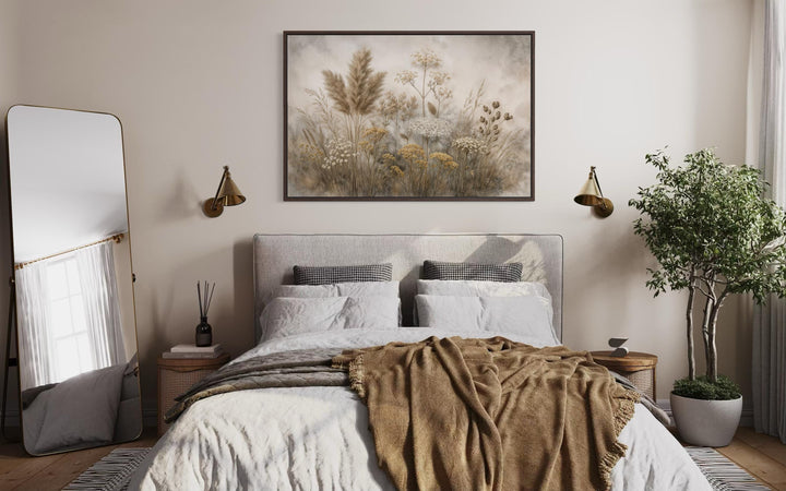 Neutral wildflowers wall art in a dark frame hangs above a bed in a modern farmhouse bedroom.