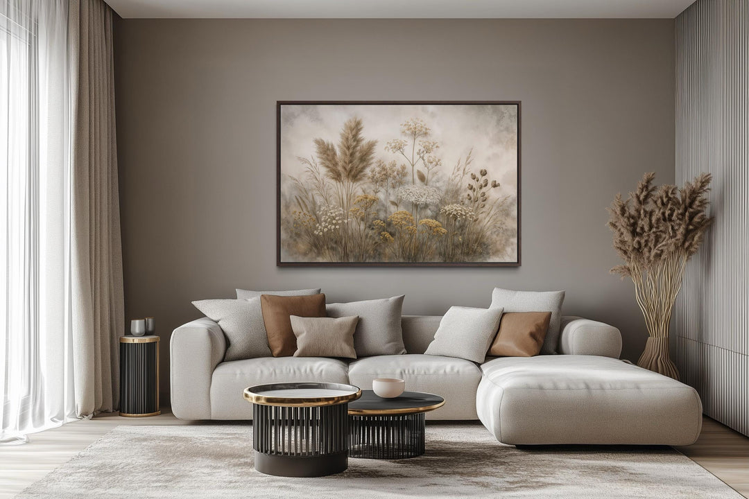 A large horizontal canvas print of neutral-toned wildflowers hangs above a modern beige sofa.