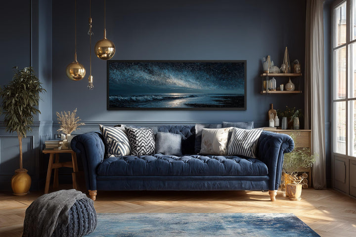 Panoramic dark blue seascape canvas print with a starry sky above a navy blue sofa.