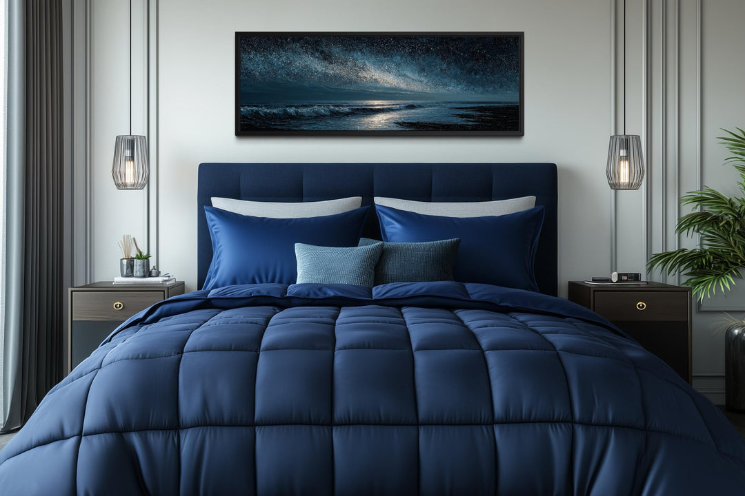 Panoramic night ocean wall art with a starry sky displayed above a navy blue bed.