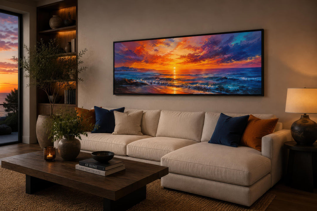Long horizontal canvas of a fiery ocean sunset with purple and orange sky above a beige sofa.
