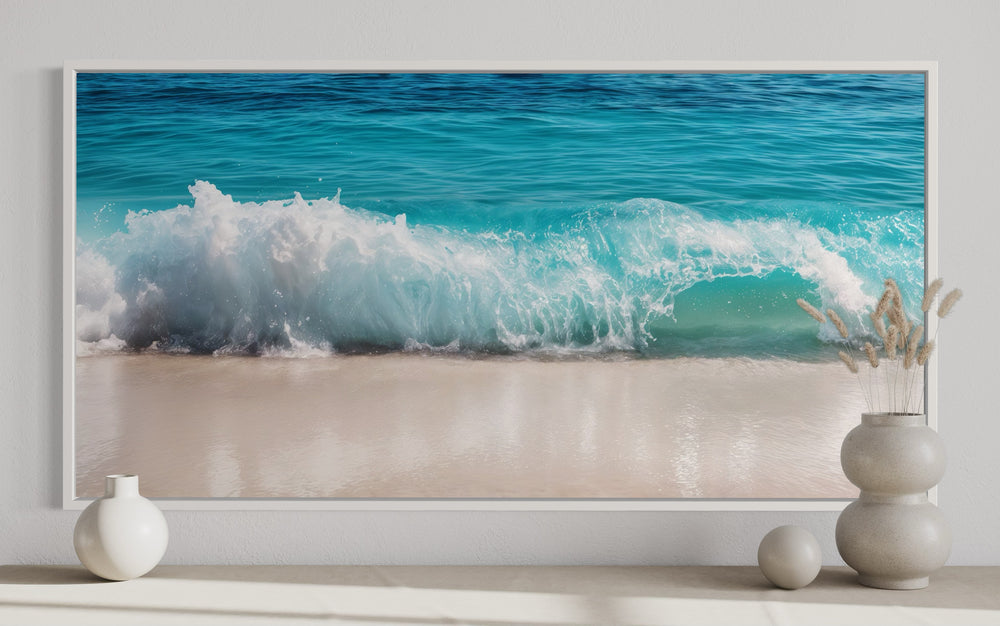 Framed coastal canvas wall art featuring a crashing turquoise ocean wave on a sandy beach.