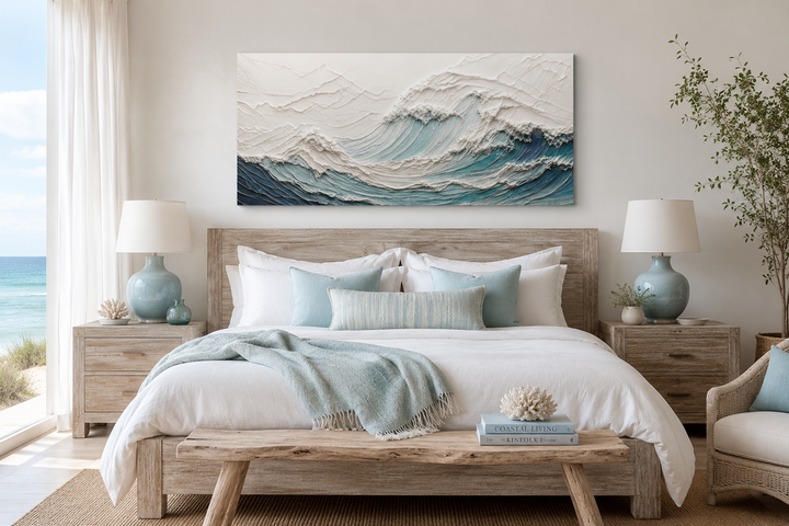 Textured teal and white ocean wave canvas art hanging above a bed in a coastal bedroom.