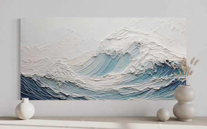 Textured teal and white ocean wave canvas art with a 3D illusion effect on a neutral wall.