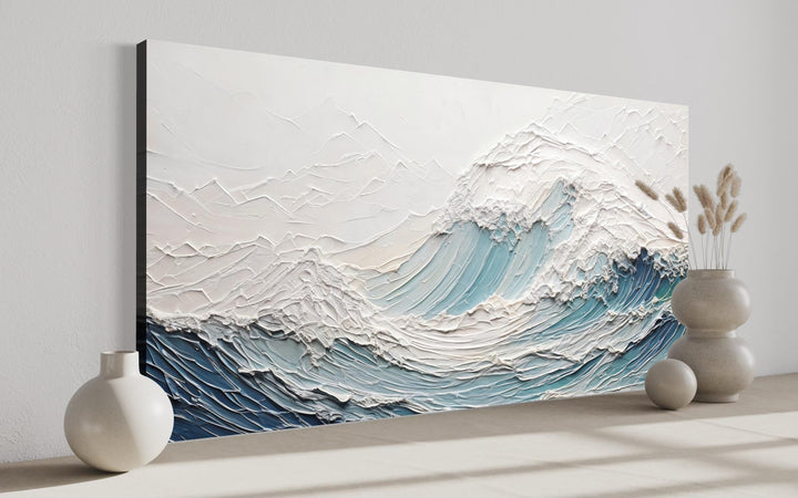 Textured teal and white ocean wave canvas art with a 3D illusion displayed in a modern room.