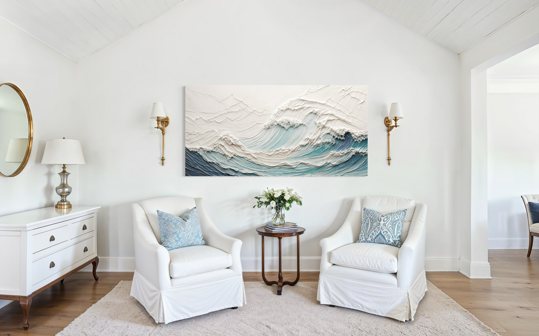Textured 3D teal ocean wave canvas art centered above two white armchairs in a bright living room.