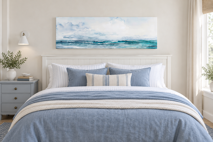 Minimalist ocean blue and gray horizontal canvas wall art hanging over a bed in a coastal bedroom.
