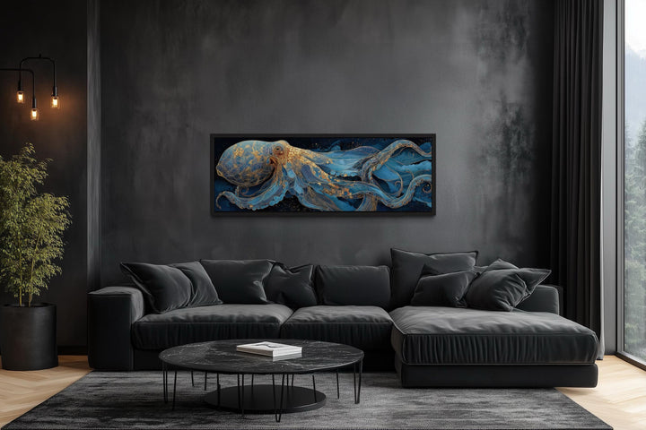 Horizontal octopus canvas wall art with blue and gold details above a black sofa in a dark room.
