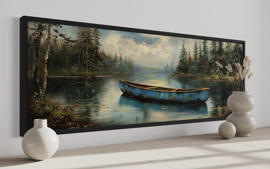 Long horizontal framed canvas wall art of an old blue canoe on a tranquil lake with forest trees.
