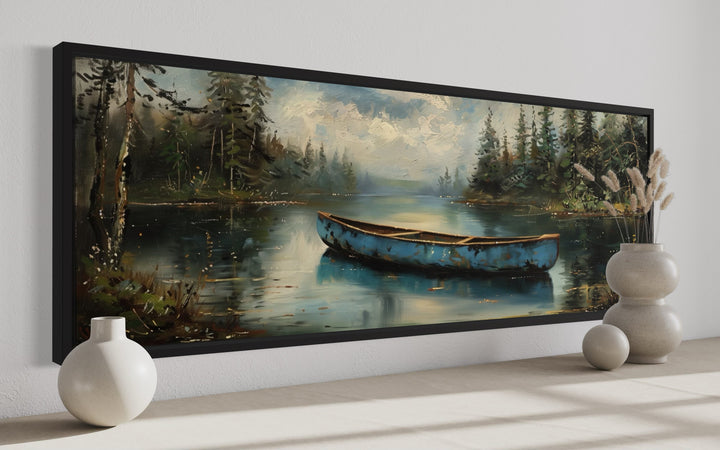 Long horizontal framed canvas wall art of an old blue canoe on a tranquil lake with forest trees.