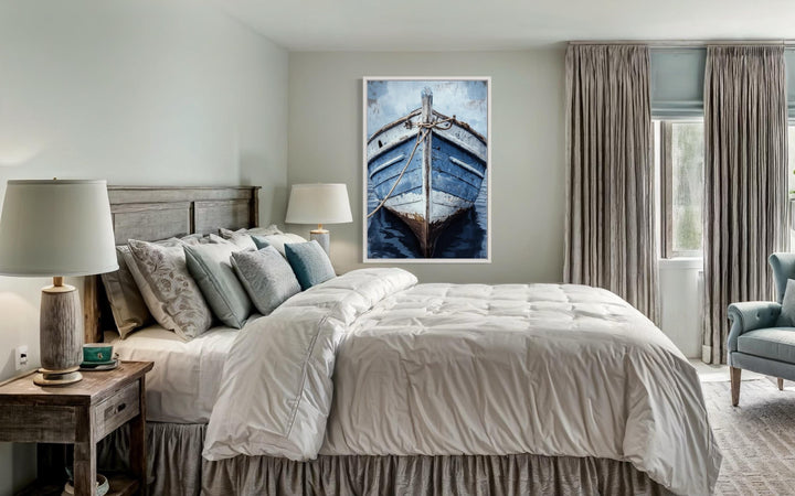 Vertical canvas wall art of a weathered blue rustic boat hanging above a bed in a coastal bedroom.