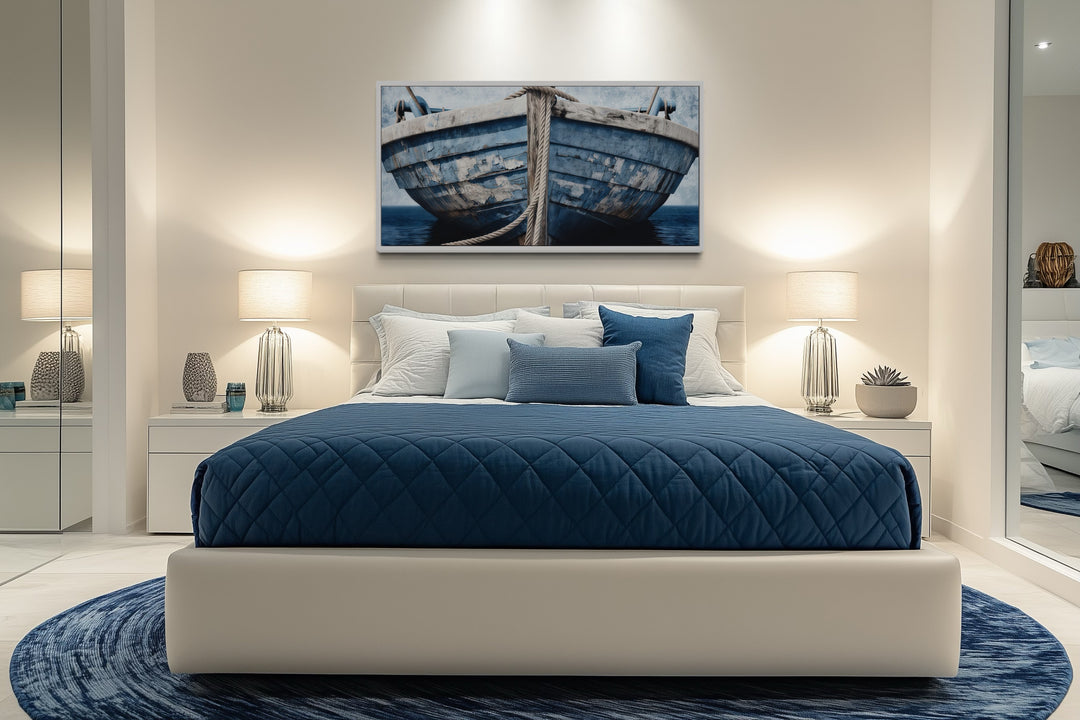 Old blue and white rustic boat nautical framed canvas wall art above a bed in a coastal bedroom.