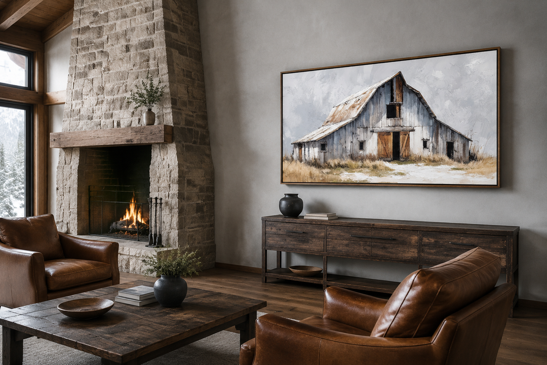 Rustic canvas wall art of an old grey barn above a wooden console in a farmhouse living room.