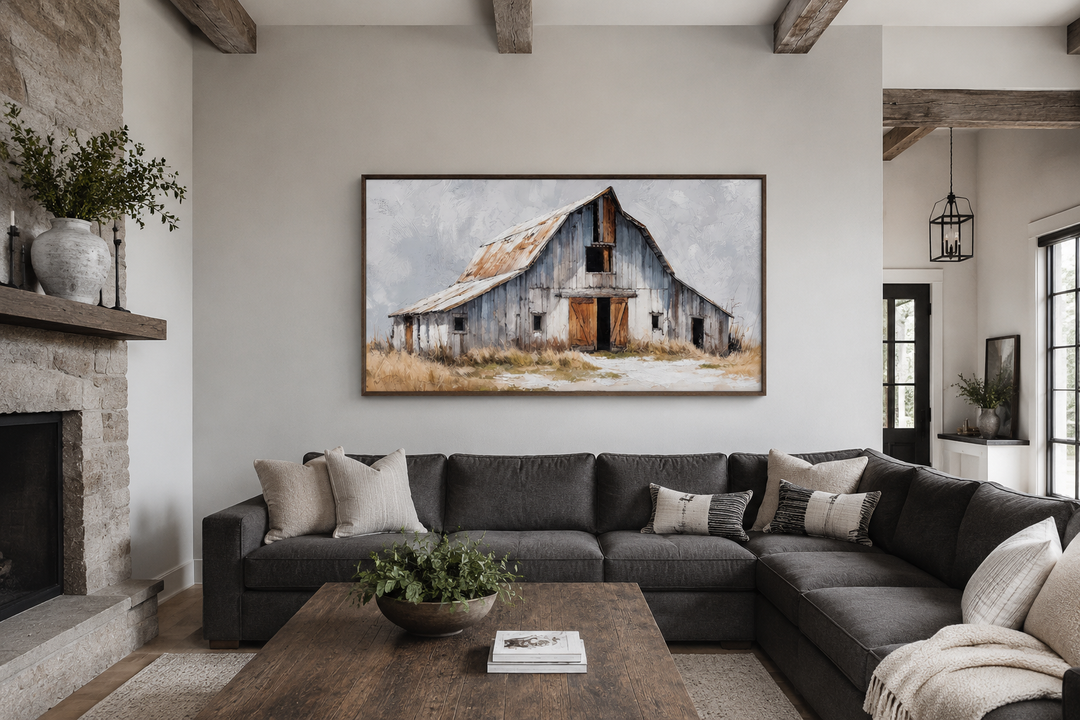 Rustic canvas wall art of an old grey barn above a dark grey sectional sofa in a farmhouse room.
