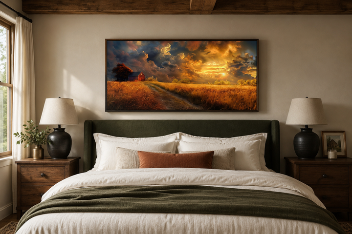 Framed canvas wall art of an old red barn in an autumn sunset landscape above a bed.