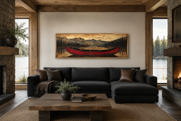 Old red canoe painted on wood long horizontal framed canvas wall art above a dark sofa in a cabin.