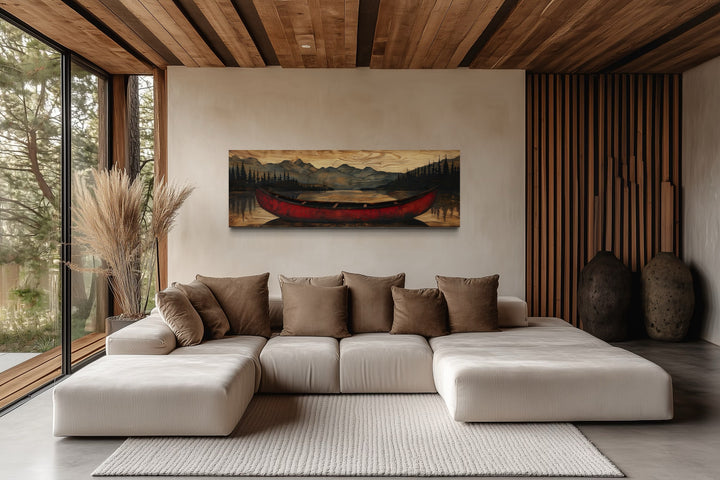 Old red canoe painted on wood long horizontal framed canvas wall art above a modern sectional sofa.