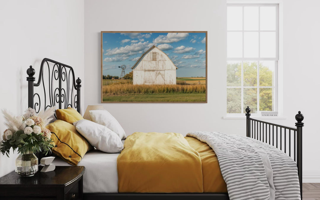 Old weathered white barn with windmill framed canvas wall art in a farmhouse bedroom setting.