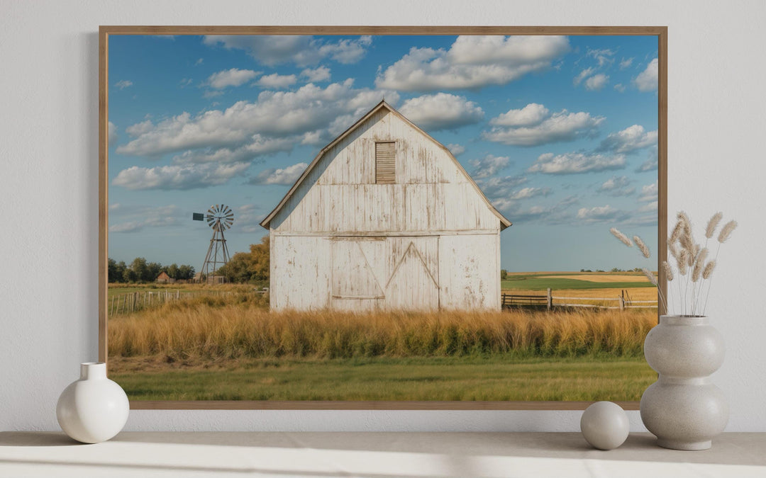 Framed canvas wall art of a weathered white barn and windmill in a golden field under a blue sky.