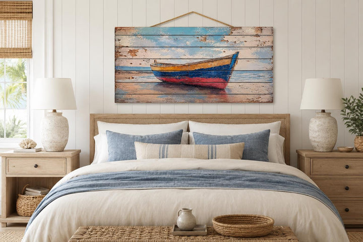 Old wooden rowboat wall art on distressed wood planks hanging above a bed in a beach house bedroom.
