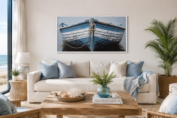 Rustic blue and white boat canvas print hanging above a sofa in a coastal-style living room.
