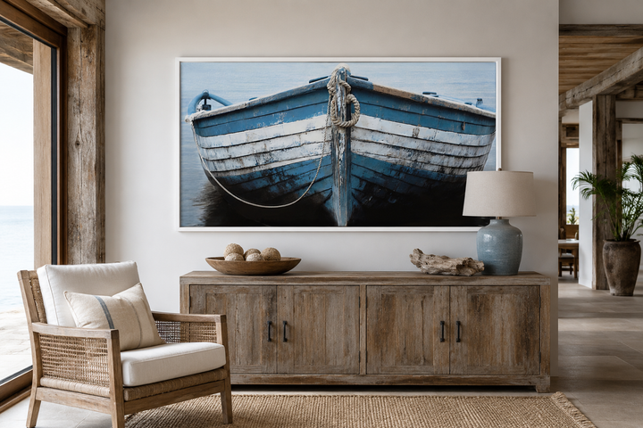 Rustic blue and white boat canvas print hanging above a wooden console in a coastal living room.
