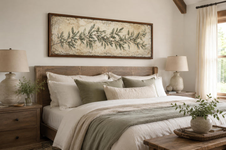 Long narrow olive branch canvas wall art in a sage green farmhouse bedroom above a wooden bed.