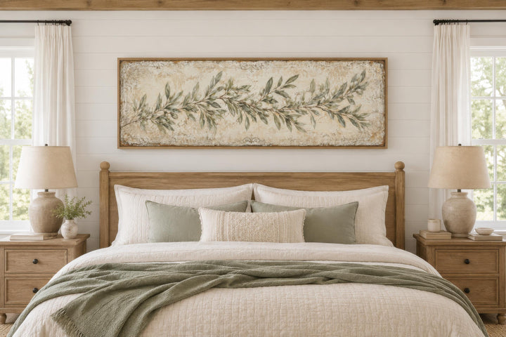 Long narrow canvas wall art featuring a sage green olive branch over a bed in a farmhouse bedroom.