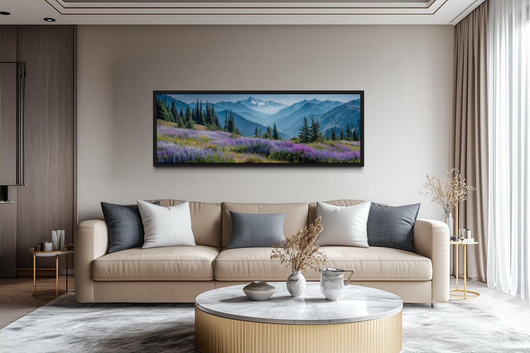 Panoramic canvas wall art of Olympic National Park mountains and purple flowers above a beige sofa.