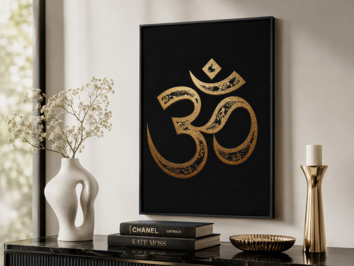 Framed gold Om symbol wall art on a black canvas displayed in a modern spiritual room setting.