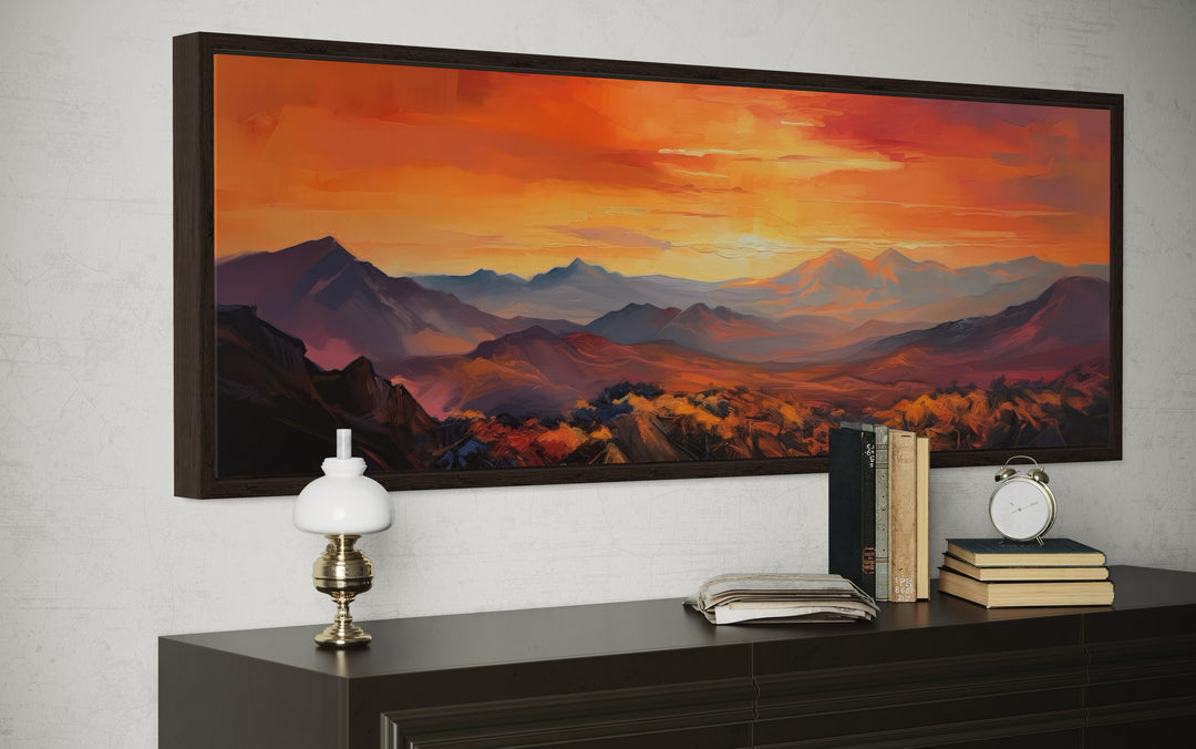 Horizontal framed canvas wall art featuring an orange mountain sunset painting above a dark dresser.