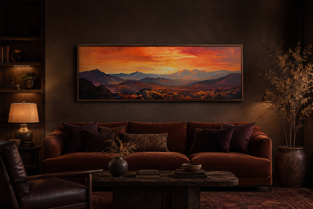 Horizontal framed canvas wall art of an orange mountain sunset above a brown velvet couch.