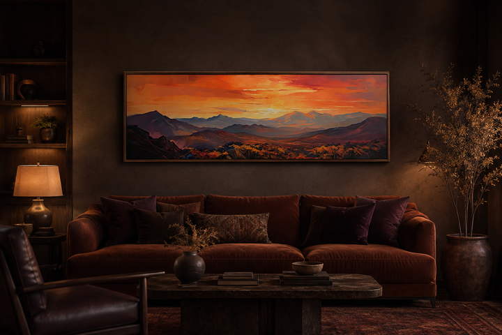 Horizontal framed canvas wall art of an orange mountain sunset above a brown velvet couch.