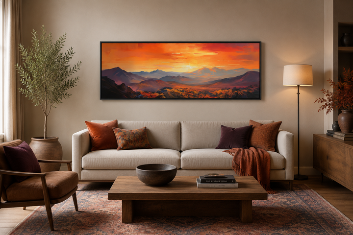 Horizontal framed canvas wall art of an orange mountain sunset above a beige couch.