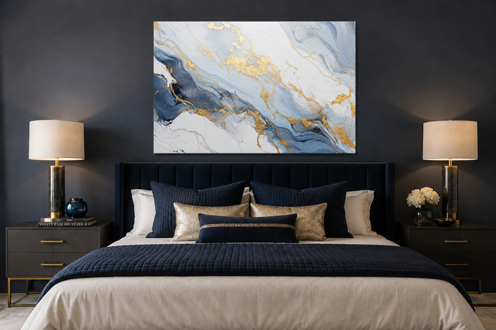 Abstract marble canvas wall art with pale blue, grey, and gold patterns above a dark navy bed.
