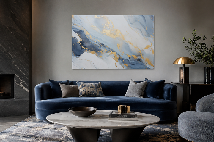 Abstract marble canvas wall art with pale blue, grey, and gold accents above a blue velvet sofa.