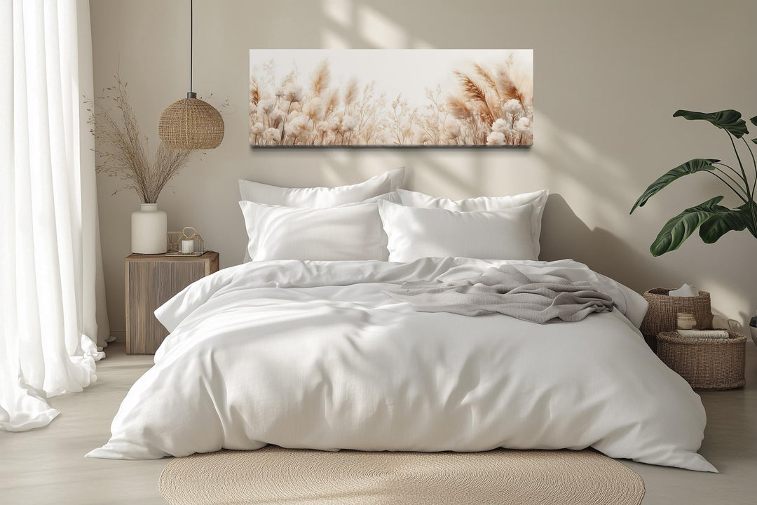 Long horizontal canvas wall art featuring neutral pampas grass stems above a white bed.