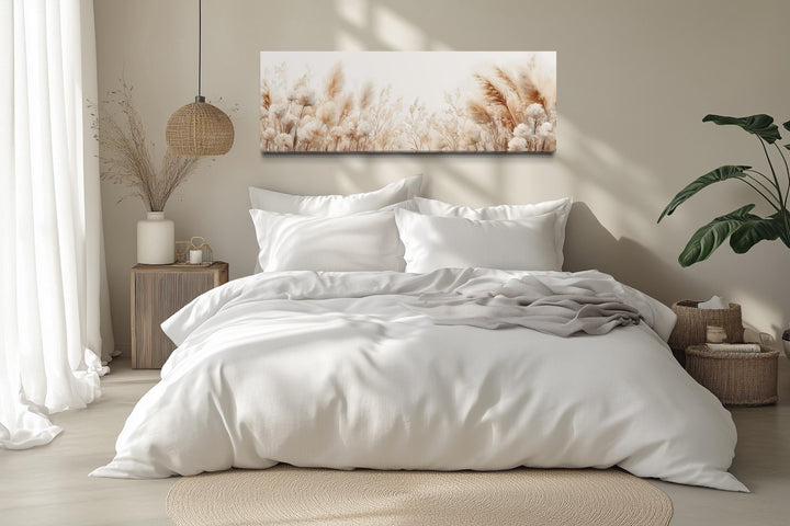 Long horizontal canvas wall art featuring neutral pampas grass stems above a white bed.