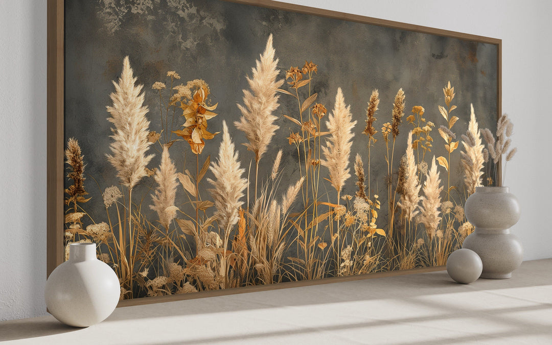 Framed canvas wall art featuring pampas grass on a textured grey background in a neutral room.