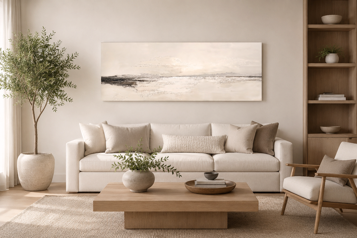 Panoramic coastal landscape canvas wall art in neutral tones hanging above a white sofa.