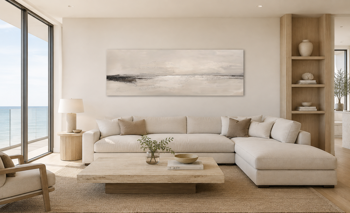 Panoramic coastal landscape canvas wall art in neutral tones hanging above a modern sofa.