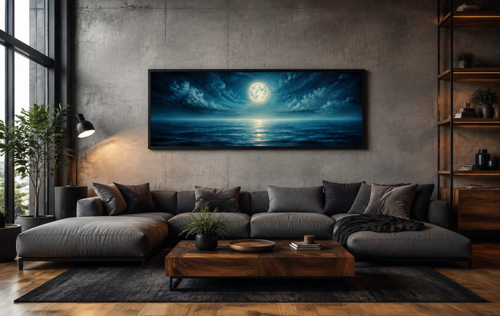 Panoramic navy blue ocean and moon in night sky wall art hanging above a modern grey sofa.