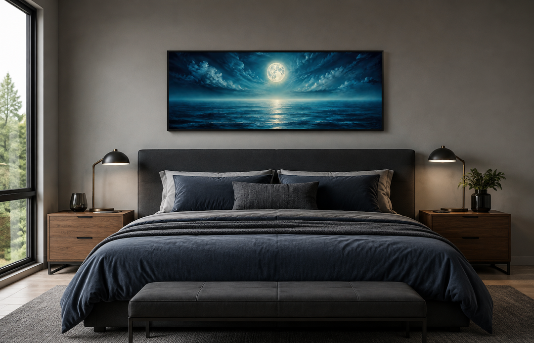 Panoramic navy blue ocean and moon wall art hanging above a modern bed in a bedroom.