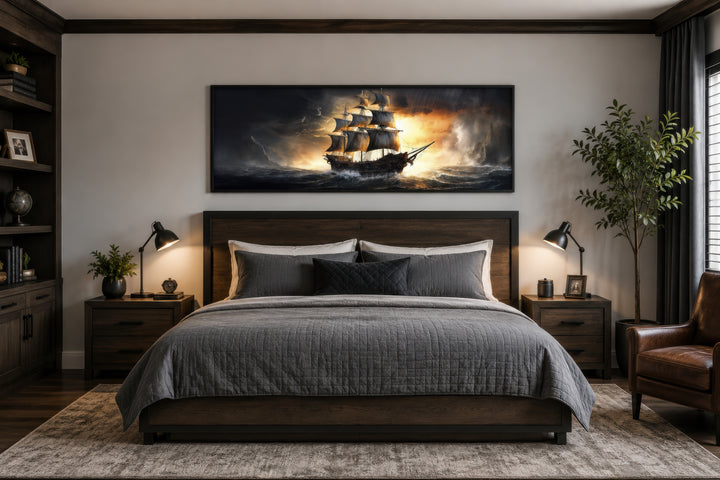 Panoramic framed canvas wall art of a pirate ship in a stormy ocean above a dark wood bed.