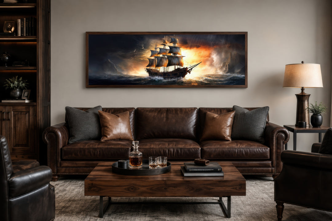 Panoramic framed canvas wall art of a pirate ship on a stormy ocean above a brown leather sofa.