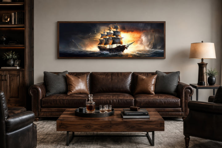 Panoramic framed canvas wall art of a pirate ship on a stormy ocean above a brown leather sofa.