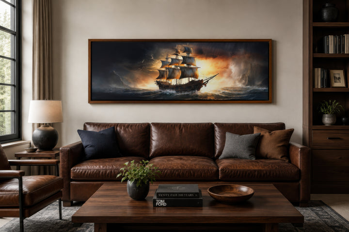 Panoramic framed canvas wall art of a pirate ship on a stormy ocean above a brown leather sofa.