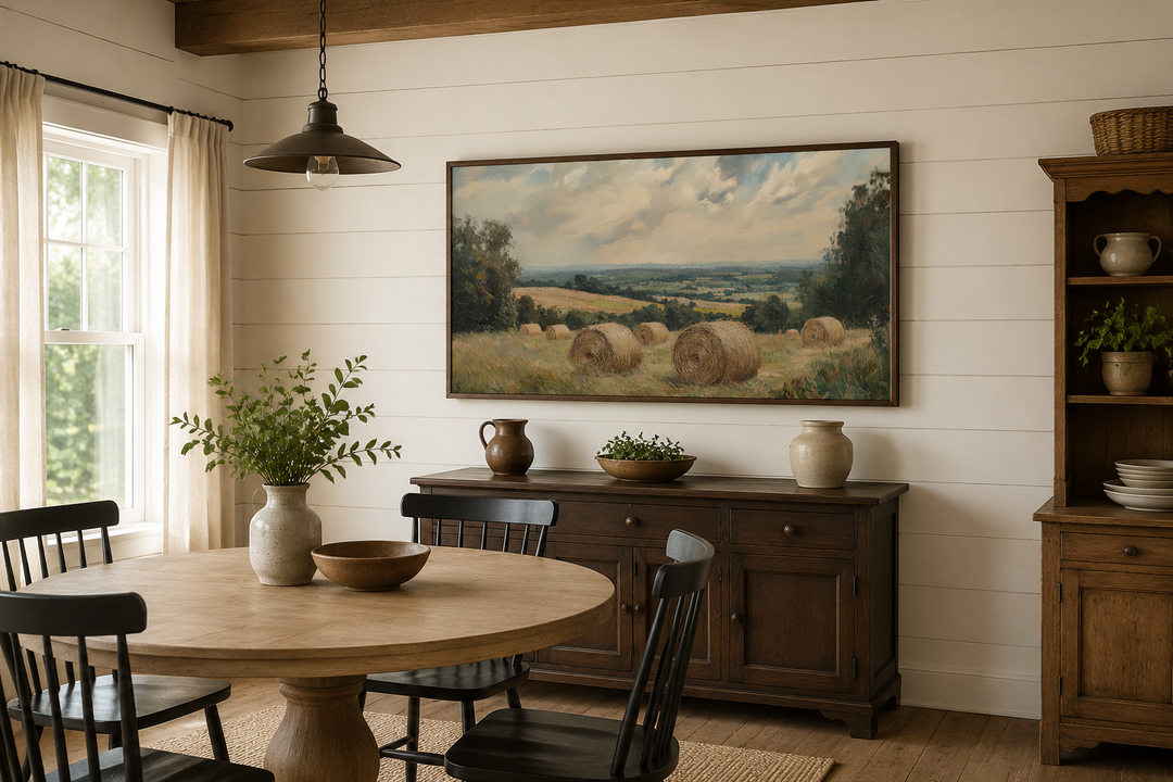 Pastoral hay field framed canvas wall art in a farmhouse dining room above a dark wood sideboard.