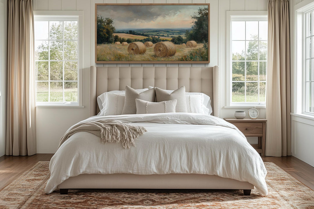 Pastoral hay field framed canvas wall art hanging above a bed in a farmhouse-style bedroom.