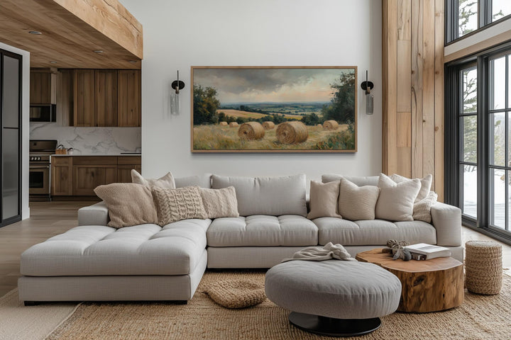 Pastoral hay field framed canvas wall art above a neutral sectional sofa in a farmhouse living room.